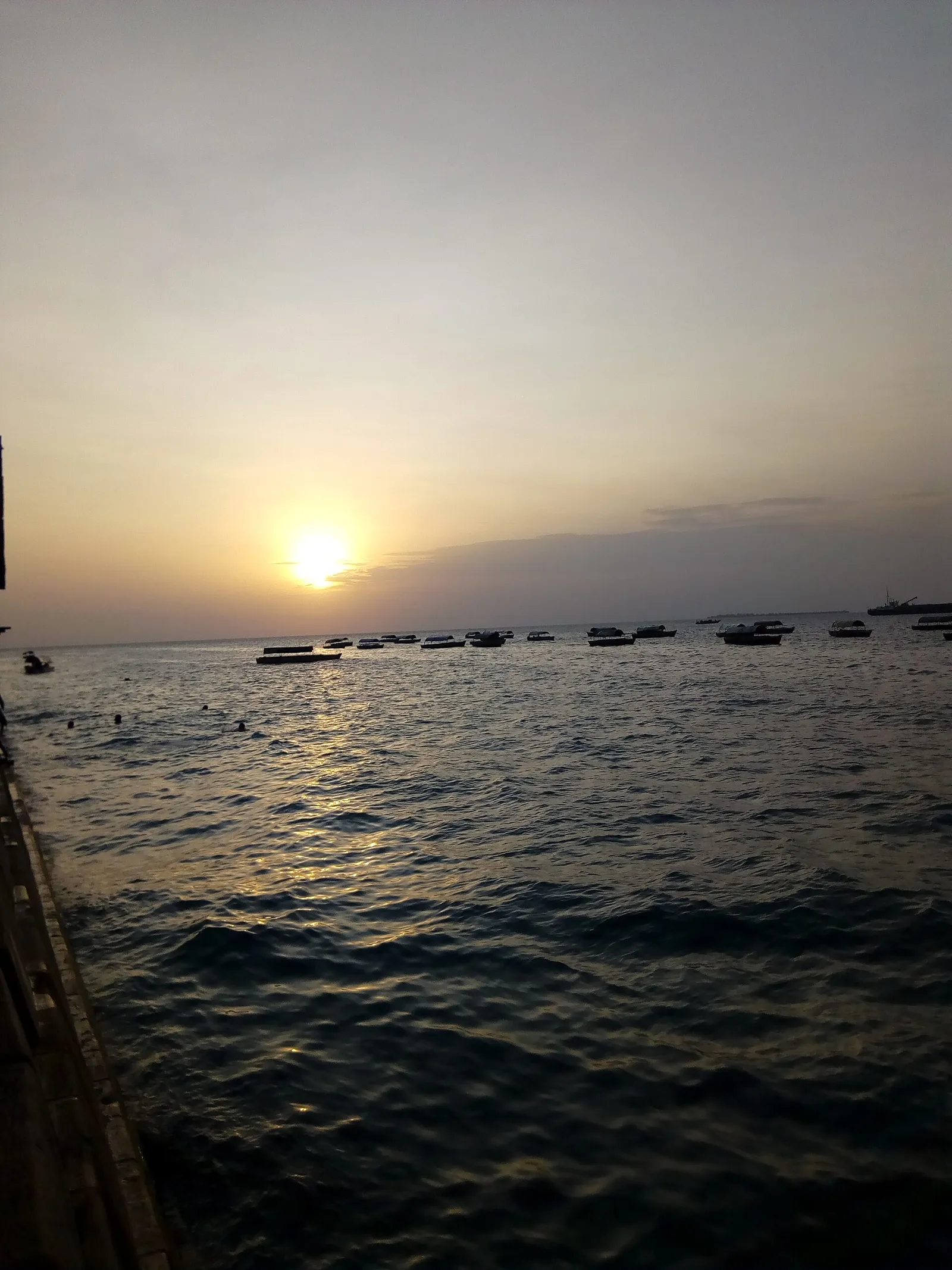 People gathered on a seafront at sunset