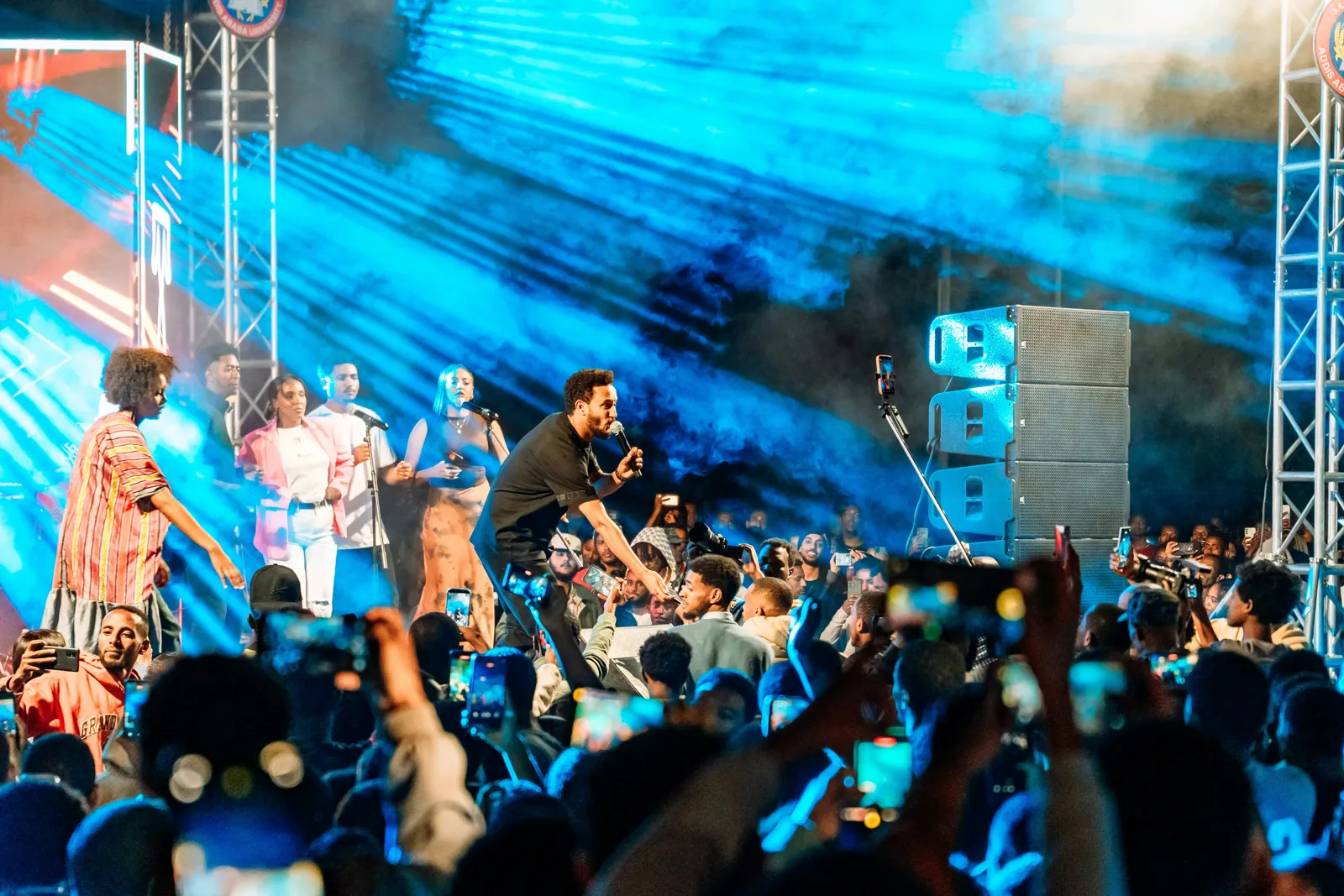 A crowd filming a band on a lit stage