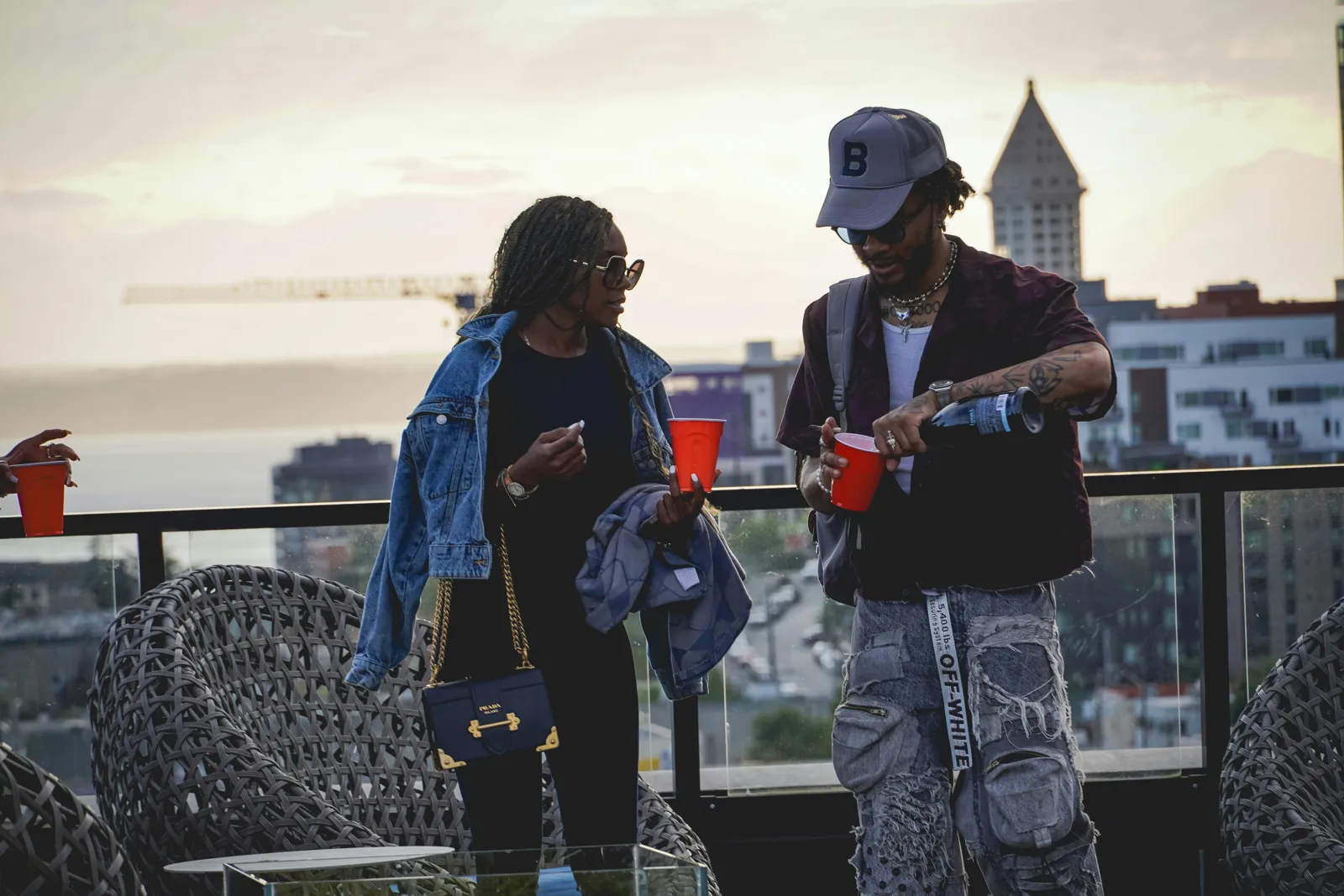 Two friends having drinks on a rooftop at sunset